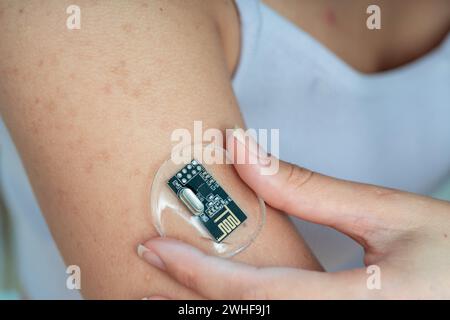 Persona che applica il sensore di monitoraggio della salute al braccio Foto Stock