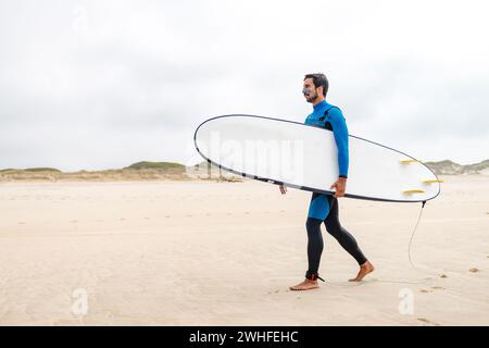 Giovane surfista che indossa la muta Foto Stock