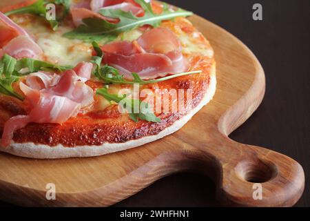 Pizza con prosciutto affumicato e Rucola su sfondo scuro Foto Stock