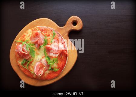 Pizza con prosciutto affumicato e Rucola su sfondo scuro Foto Stock