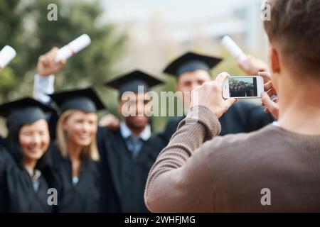 Gruppo, studenti e posa per foto, lauree e risultati con i social media ed entusiasti. Persone, schermo dello smartphone e amici con diploma e. Foto Stock