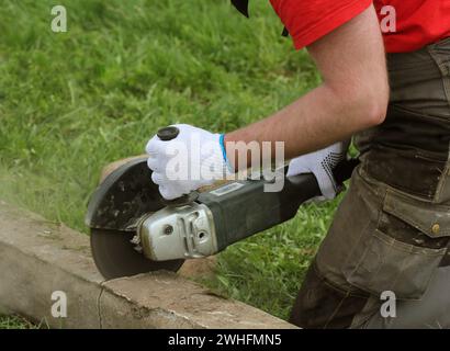 Operaio edile di taglio piastra di calcestruzzo per la fondazione di recinzione utilizzando una troncatrice Foto Stock