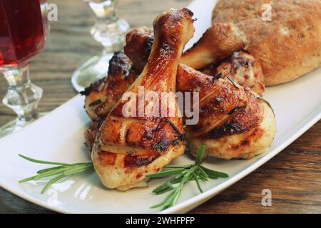 Grigliata di cosce di pollo con rosmarino servita su piastra bianca. La cena sullo sfondo Foto Stock