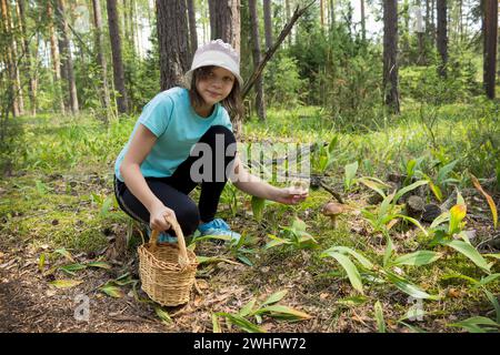 L'adolescente nella foresta raccoglie i funghi Foto Stock