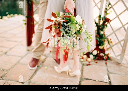 Bouquet di fiori legati con un nastro nella mano della sposa. Ritagliato Foto Stock