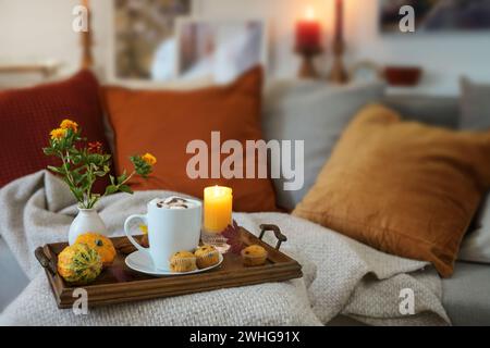 Rilassatevi con cioccolata calda su un vassoio con candele e decorazioni autunnali sul divano in un accogliente soggiorno, spazio fotocopie, selezione Foto Stock