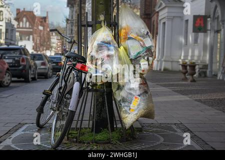 Lubecca, Germania, 11 aprile 2022: Sacchetti per la spazzatura con materiale di riciclaggio raccolto appeso su una struttura ad albero accanto a una bicicletta, rifiuti Foto Stock