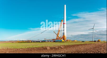 Costruzione e assemblaggio di una turbina eolica da costruzione tramite gru. Terreni agricoli con lavori di costruzione Foto Stock