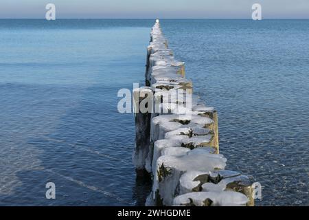 Inguine di legno con calotte di ghiaccio sulla spiaggia della costa del Mar Baltico nella Germania settentrionale, spazio copia, messa a fuoco selezionata, profondità ridotta Foto Stock