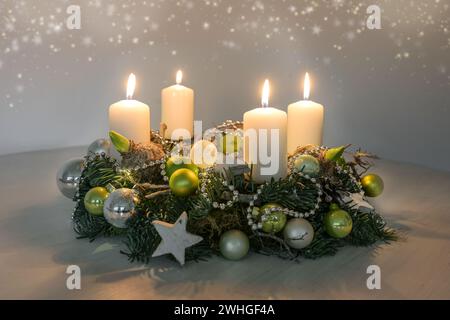 Quarto Avvento, corona con quattro candele bianche bruciate e decorazioni natalizie verdi su un tavolo, arredamento per la quarta Sunda Foto Stock