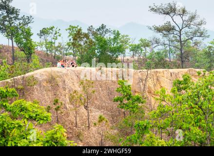 PAI, Mae Hong Son, Thailandia - 9 aprile 2023: Giovani viaggiatori arroccati in cima a un lontano precipizio, in questo paesaggio erboso e naturale Foto Stock