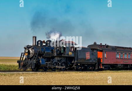 Vista di un classico treno passeggeri a vapore che passa da fumo e vapore in un giorno di sole Foto Stock