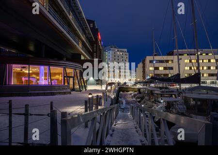 Europa, Norvegia, porto di Tromso di notte con barche ormeggiate in inverno vicino allo Scandic Ishavshotel Foto Stock