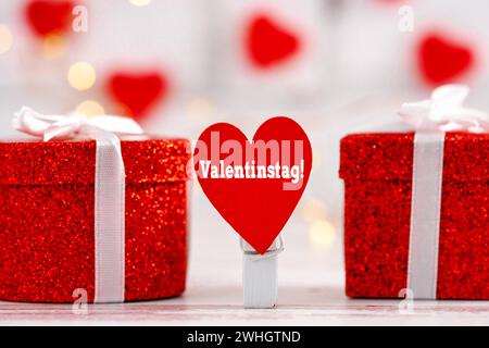 10 febbraio 2024: San Valentino scrivendo su un cuore rosso accanto ai regali FOTOMONTAGGIO *** Valentinstag Schrift auf einem roten Herz neben Geschenken FOTOMONTAGE Foto Stock