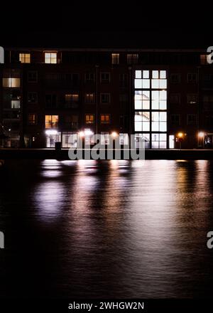 Vista sul fiume con edifici illuminati e riflessi sull'acqua Foto Stock