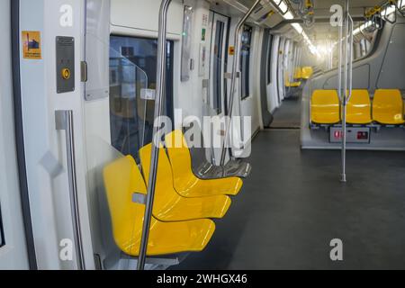 Interno di un'autovettura di un treno pendolare. Sedili in plastica gialla e corrimano cromati all'interno di un vagone ferroviario elettrico. Foto Stock
