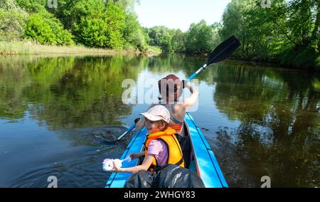 Gita in kayak per tutta la famiglia. Mamma e figlia remando una barca sul fiume, un'escursione in acqua, un'avventura estiva. Ecocompatibile ed estremo touri Foto Stock