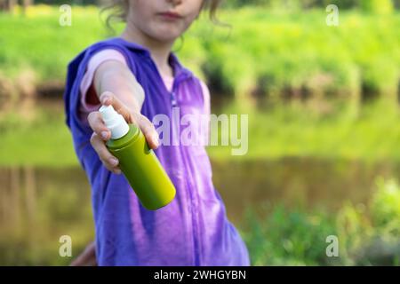 La ragazza spruzza sulla pelle uno spray di zanzara che morde mani e piedi. Protezione da punture di insetti, repellente sicuro per Foto Stock