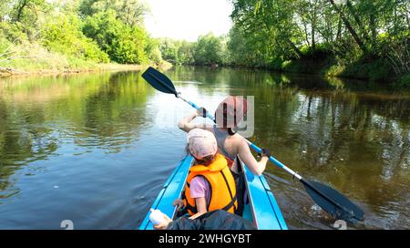 Gita in kayak per tutta la famiglia. Mamma e figlia remando una barca sul fiume, un'escursione in acqua, un'avventura estiva. Ecocompatibile ed estremo touri Foto Stock