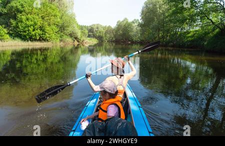 Gita in kayak per tutta la famiglia. Mamma e figlia remando una barca sul fiume, un'escursione in acqua, un'avventura estiva. Ecocompatibile ed estremo touri Foto Stock