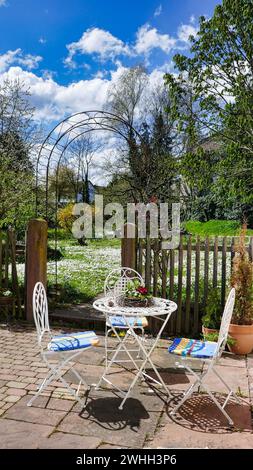 Accogliente angolo giardino con tavolo e sedia e un prato fiorito sullo sfondo Foto Stock