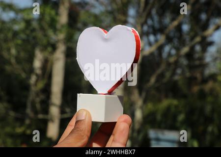 Forma del cuore realizzata con stampante 3d tenuta in mano con uno sfondo naturale. Concetto che mostra l'amore verso la natura o il cuore puro Foto Stock