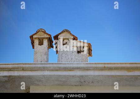 Camini in gesso chiaro con tetti piastrellati su un edificio in Grecia, che sembrano piccole case, cielo blu con spazio copia, selecte Foto Stock