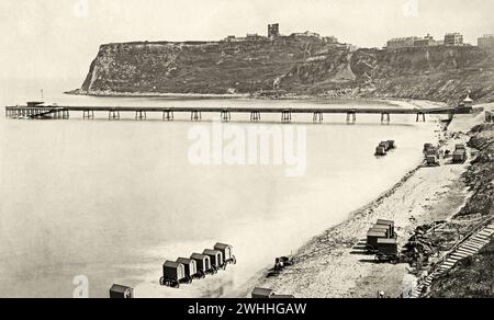 Una vecchia vista vittoriana di Scarborough North Pier, un piroscafo e un molo per passeggiate, a North Bay, Scarborough, North Yorkshire, Inghilterra, Regno Unito c.1880. Questa vista mostra anche le macchine da bagno (cambio capanne su ruote) sulla spiaggia. Progettato da Eugenius Birch, il molo fu aperto nel 1869. Nel 1905 fu distrutto da una tempesta lasciando solo il padiglione d'ingresso e una testa di molo isolata. In seguito la testa del molo fu demolita lasciando l'edificio d'ingresso, a sua volta demolito nel 1914. Foto Stock