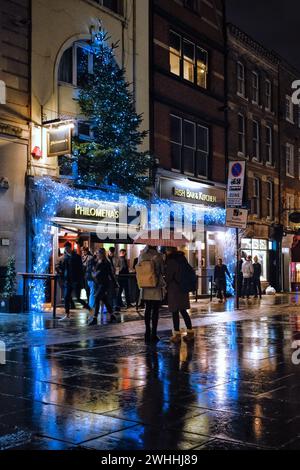 Natale a Covent Garden. Una coppia sotto un ombrello sotto la pioggia fuori dal bar Philomenas. Covent Garden a Londra, Regno Unito, il 10 febbraio 2024. Foto di Julie Edwards. Foto Stock