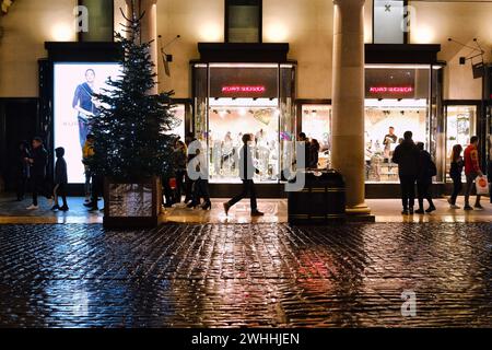 Natale a Covent Garden. Le luci del negozio Kurt Geiger si riflettono sui ciottoli bagnati. Covent Garden a Londra, Regno Unito, il 10 febbraio 2024. Foto di Julie Edwards. Foto Stock