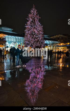 Natale a Covent Garden. Una coppia in cappelli di Babbo Natale con l'albero di Natale sullo sfondo. Covent Garden a Londra, Regno Unito, il 10 febbraio 2024. Foto di Julie Edwards. Foto Stock