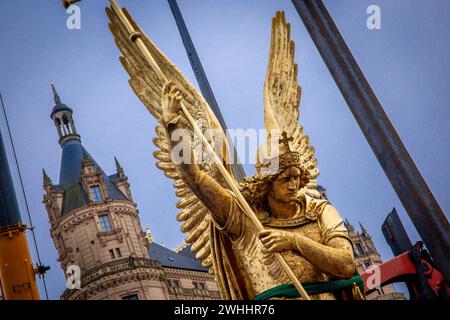 Schwerin, Germania. 8 febbraio 2024. L'Arcangelo Michele viene rimosso dalla cupola d'oro del castello di Schwerin per lavori di restauro utilizzando una gru mobile e caricato su un camion per il trasporto in un'officina. La figura risale al 1857 ed è ufficialmente chiamata "Arcangelo Michele che uccide il drago". L'arcangelo viene ora pulito, restaurato e ridorato in un laboratorio di Berlino prima di tornare al castello in estate. L'Arcangelo Michael Slaying the Dragon è stato restaurato l'ultima volta 30 anni fa. Crediti: Jens Büttner/dpa/Alamy Live News Foto Stock