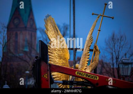 Schwerin, Germania. 8 febbraio 2024. L'Arcangelo Michele viene rimosso dalla cupola d'oro del castello di Schwerin per lavori di restauro utilizzando una gru mobile e caricato su un camion per il trasporto in un'officina. La figura risale al 1857 ed è ufficialmente chiamata "Arcangelo Michele che uccide il drago". L'arcangelo viene ora pulito, restaurato e ridorato in un laboratorio di Berlino prima di tornare al castello in estate. L'Arcangelo Michael Slaying the Dragon è stato restaurato l'ultima volta 30 anni fa. Crediti: Jens Büttner/dpa/Alamy Live News Foto Stock