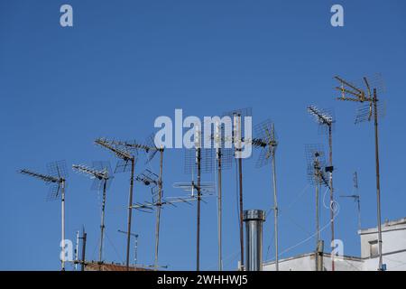 Varie antenne sul tetto di un condominio residenziale per comunicazioni e media come tv, Internet, smartphone e Foto Stock