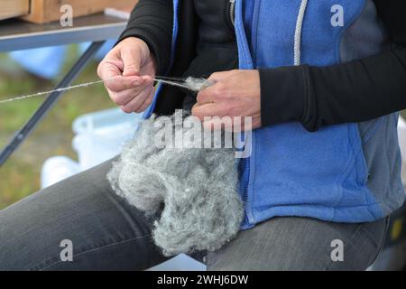 Le mani di una donna che filtra lana grigia grezza in un mercato artigianale, con un focus selezionato Foto Stock