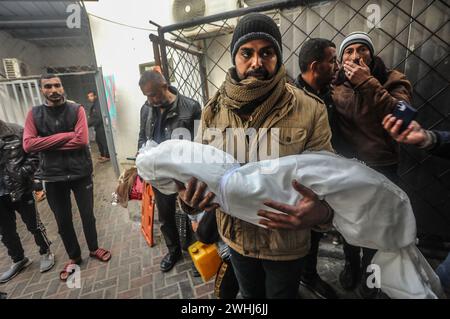 Rafah, Gaza. 9 febbraio 2024. Un uomo palestinese trasporta il corpo di un bambino ucciso durante un bombardamento israeliano notturno nella striscia di Gaza meridionale, all'ospedale al-Najjar di Rafah, sabato 10 febbraio 2024. 22 persone sono state uccise bombardamenti israeliani a Rafah compresi sfollati dal nord di Gaza, hanno detto i testimoni. Foto di Ismael Mohamad/UPI. Crediti: UPI/Alamy Live News Foto Stock