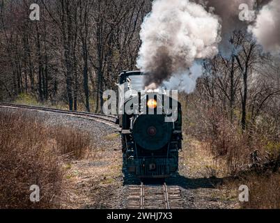 Vai sopra e sopra la vista di un treno a vapore passeggeri a scartamento ridotto restaurato che soffia fumo Foto Stock