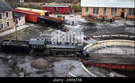 Drone Vista di una locomotiva a vapore a carreggiata stretta che scende da un giradischi e prepara il vapore per le giornate di lavoro Foto Stock