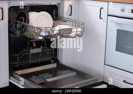 Molti piatti sporchi in lavastoviglie. Aiutare la padrona di casa, l'economia e l'ecologia. Pulizia in cucina Foto Stock