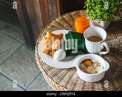 Colazione in stile thailandese. Vista dall'alto verso il basso su uno sfondo di un tavolo in rattan. Patongko, riso appiccicoso con maiale avvolto in foglie di banana, boi Foto Stock