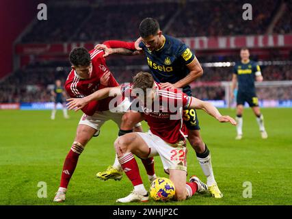 Bruno Guimaraes (in alto a destra) del Newcastle United combatte per il pallone con Ryan Yates e Neco Williams del Nottingham Forest durante la partita di Premier League al City Ground di Nottingham. Data foto: Sabato 10 febbraio 2024. Foto Stock