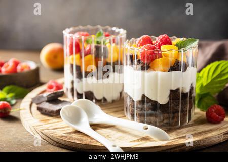 Colazione estiva a base di dieta salutare, concetto di snack. Triffle di biscotti al cioccolato con yogurt, frutti di bosco e frutta fresca. Due porzioni Foto Stock