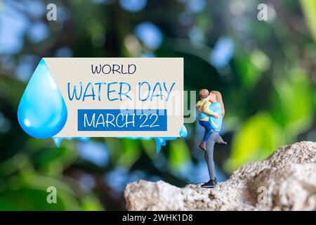 Persone in miniatura madre che tiene il figlio tra le braccia e parole scritte sulla carta giornata Mondiale dell'acqua Foto Stock