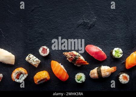 Sushi, sparato dall'alto. Rotoli, maki, nigiri su sfondo ardesia nera Foto Stock