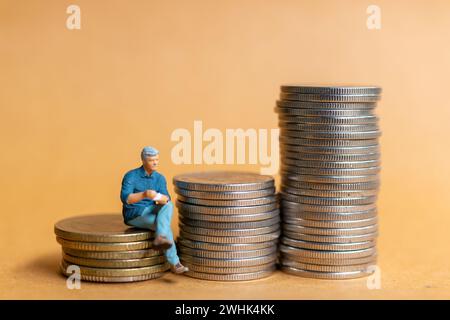 Persone in miniatura, uomo d'affari seduto su una pila di monete Foto Stock