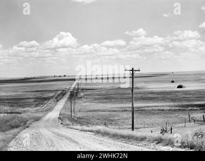 Strada sterrata attraverso il paesaggio rurale con ascensori per cereali sullo sfondo, Homestead, Montana, USA, Marion Post Wolcott, U.S. Farm Security Administration, agosto 1941 Foto Stock