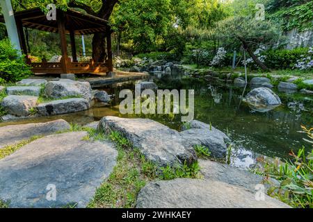 Paesaggio di un gazebo di legno accanto a un piccolo stagno con una piccola cascata in un parco pubblico della Corea del Sud Foto Stock