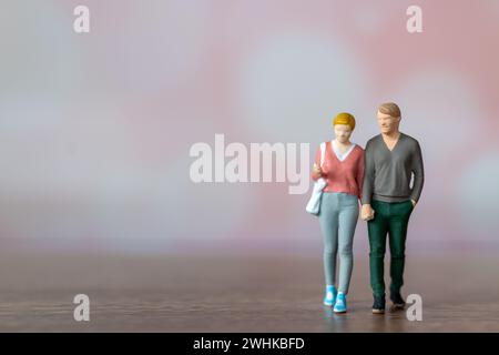 Persone in miniatura uomo e donna in un panno casual in piedi insieme su sfondo rosa Foto Stock