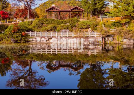 Riflessi di tavoli da picnic coperti sulla collina accanto al piccolo laghetto artificiale in Corea del Sud Foto Stock