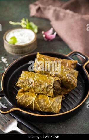 Delizioso dolma - foglie d'uva ripiene con riso e carne su sfondo di pietra scura. Greco tradizionale, caucasico e turco c Foto Stock